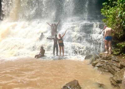 swim in the pool beneath a waterfall during raining season in Bomfobiri, just like our guests in this picture
