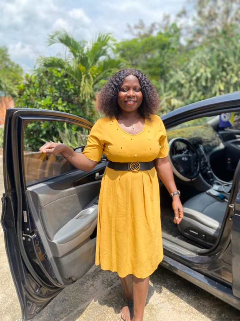 auto huren in Ghana. Supervisor Dorcas poseert voor onze auto bij BWO Hostel